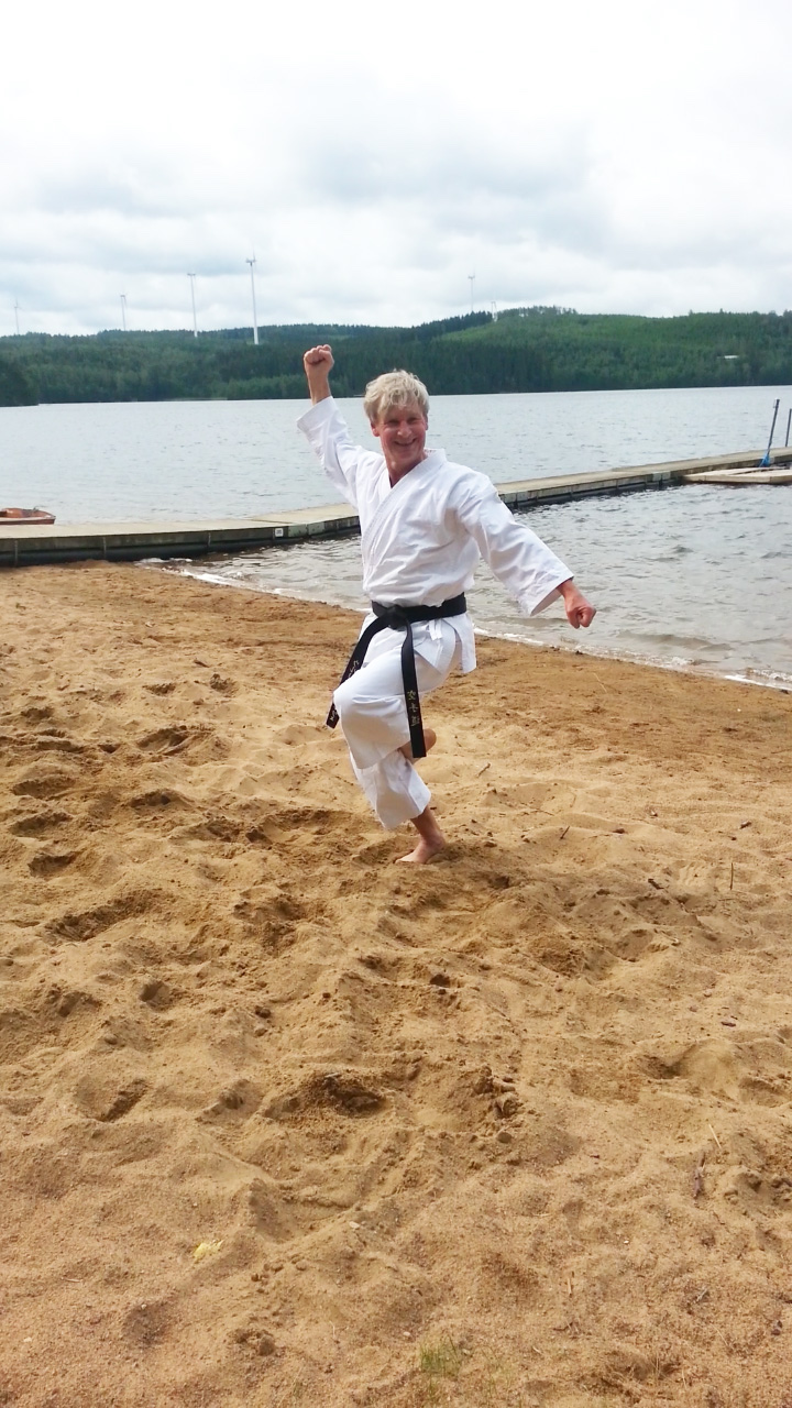Ulrich Schulze macht im Karateanzug eine Karatepose am Strand