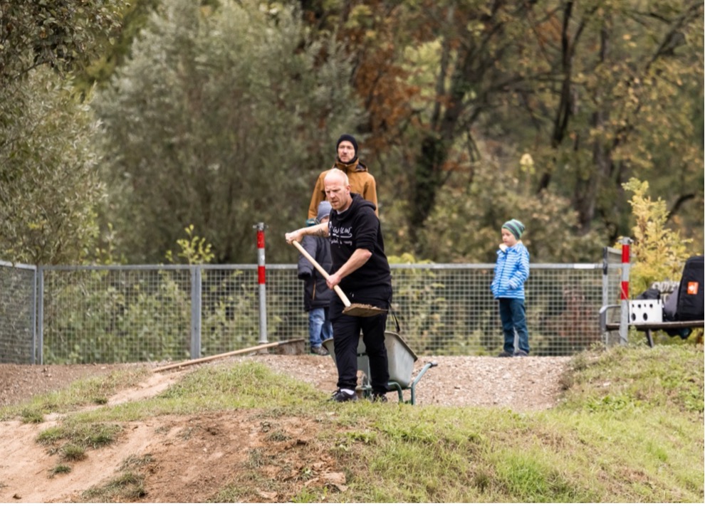 Ein Mand steht mit einer Schaufel in der Hand auf einem Hügel