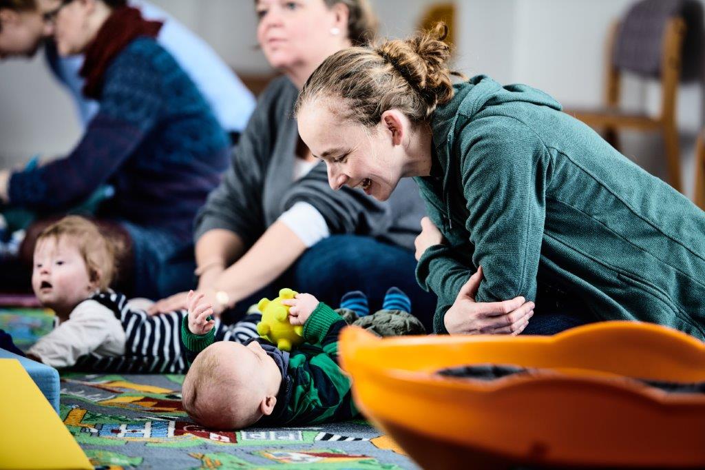Eine Mutter spielt mit ihrem Baby auf dem Boden.
