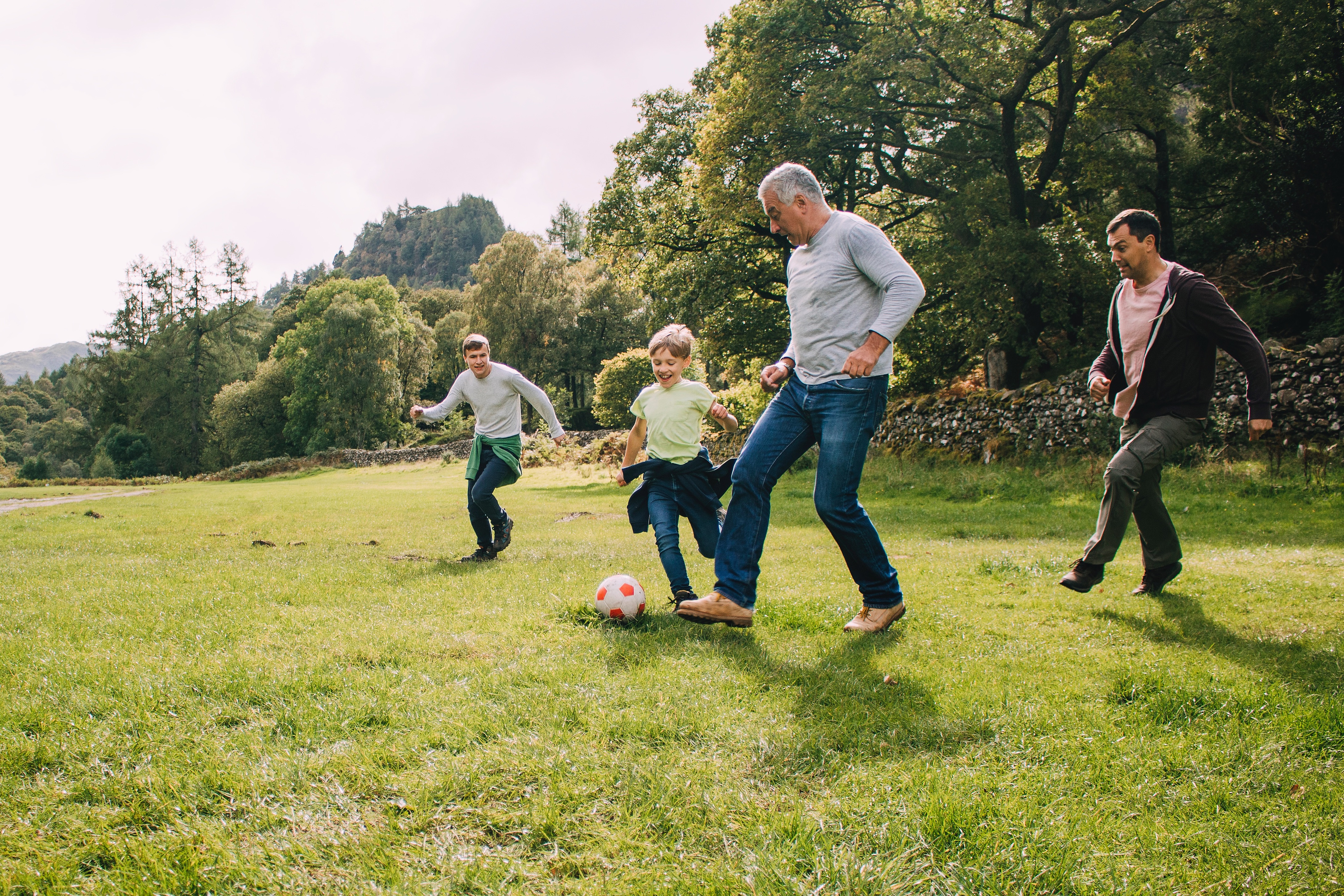 Kinder spielen Fußball mit ihrem Opa.