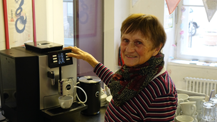 Frau mit braunen Haaren bedient eine Kaffeemaschine