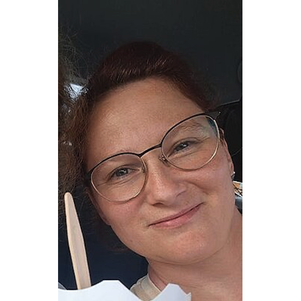 Ein Frau mit Brille lächelt in die Kamera. Es ist nur ihr Gesicht zu sehen. 